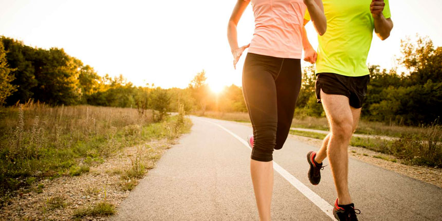 A man and woman jogging together on an outdoor trail during sunset, promoting fitness and healthy lifestyle