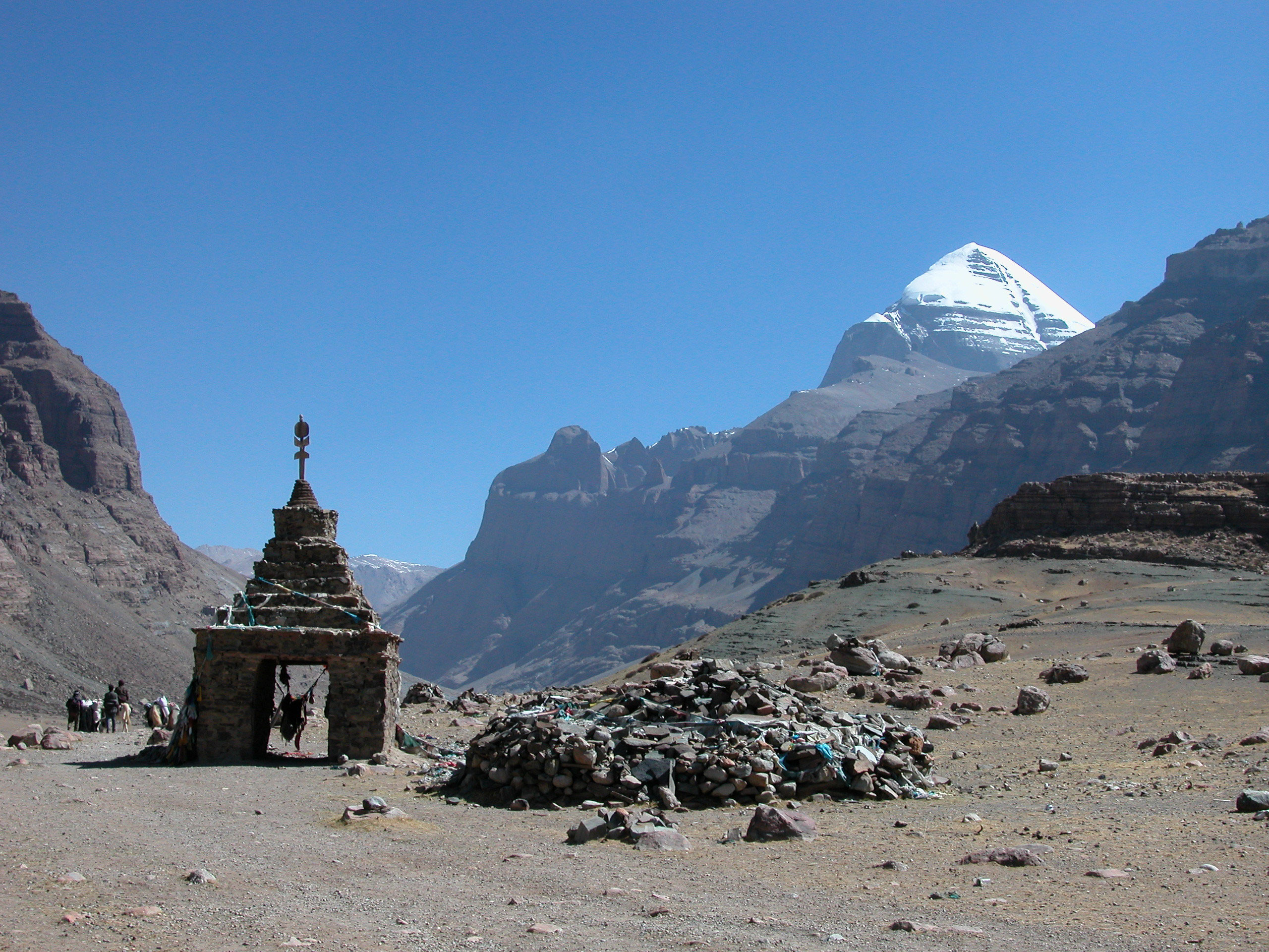 Mount Kailash view during parikrama with Tibetan stupa and stone piles, sacred Himalayan pilgrimage site for Hindus, Buddhists, Jains, and Bon